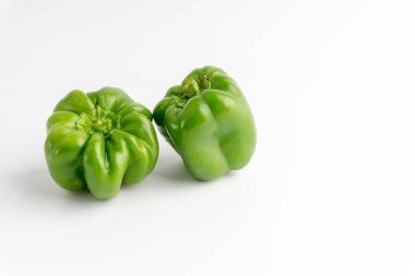 Beyaz arka planda taze yeşil dolma biber (capsicum). Seçici odak ve kırpma parçası