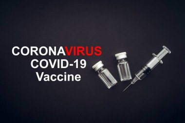 CORONAVIRUS COVID-19 VACCINE metin üzerinde şırınga ve şişeler siyah arka planda. Covid-19 ve Coronavirus konsepti