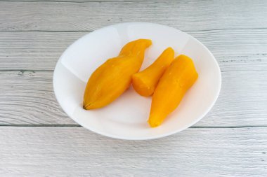 Ubi rebus ya da buharlı cassava, ahşap arka planda bulunan geleneksel Malay tabağıdır. Seçici odak