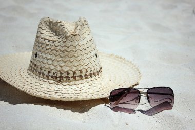 Hasır şapka ve gözlük kum üzerinde. Retro arka plan.