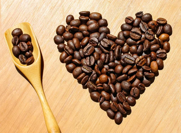 Heart of coffee beans with wooden spoon on a wooden background. I love coffee concept.