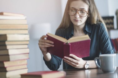 Genç kız masanın üzerinde kitap okuma