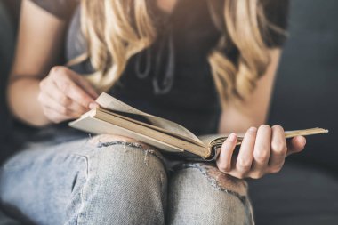 Kanepede kitap okuyan genç bir kadın.