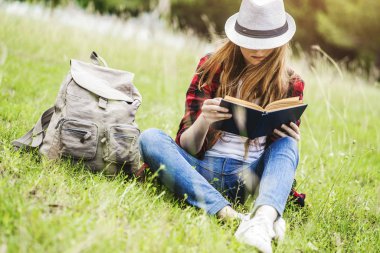 Oturma ve çimlerin üzerine kitap okuma kız