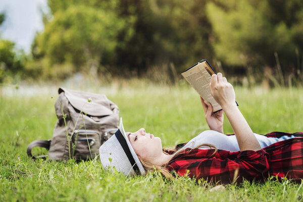 Девушка лежит и читает книгу о траве
