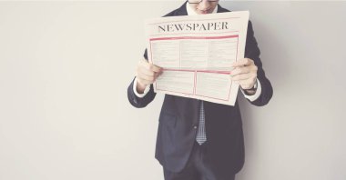 İşadamı gazete gri arka plan üzerinde okuma