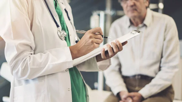 Gesundheitshelferin Macht Sich Notizen Von Älterer Männlicher Patientin — Stockfoto