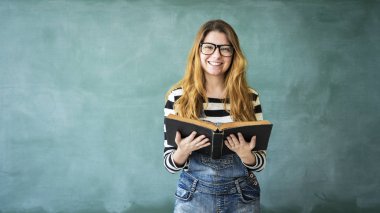 Genç öğrenci kız yeşil kara tahta kitap okuma