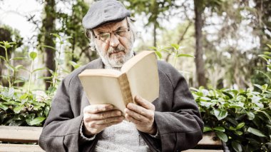 Yaşlı adam parkta kitap okumak