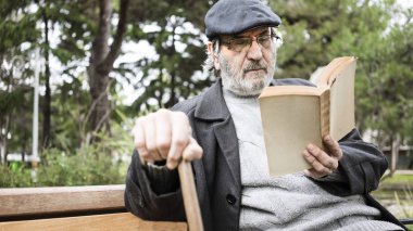 Yaşlı adam parkta kitap okumak