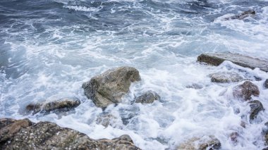 Deniz dalgaları kayalara çarpıyor.