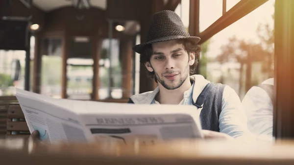 Young man reading newspaper in the bus