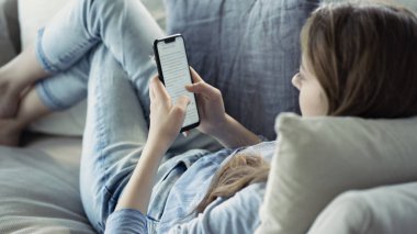 Evde cep telefonu kullanan genç bir kadın.