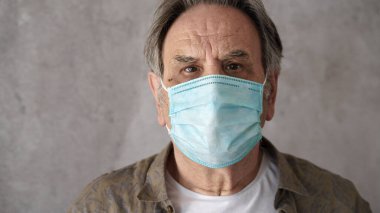 Tıbbi maske takan yaşlı adam.