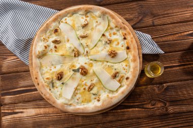 Ahşap bir arka planda armut, fındık ve mavi peynir ile geleneksel pizza. Kapat şunu. Üst görünüm.
