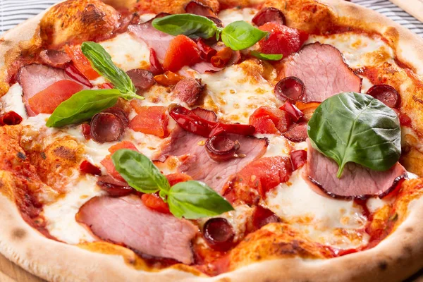 Pizza with ham , arugula (salad rocket), rucola and mozzarella  on  wooden background close up. Italian cuisine.