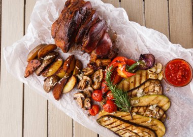 Izgara domates, champignons, vagetable ilik, patlıcan, kırmızı tatlı biber ve pişmiş patates ve parşömen ahşap kesme tahtası ile ızgara domuz eklem. üst görünüm
