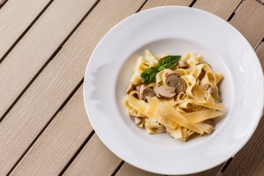 Fesleğen ile süslenmiş Mantarlı Tagliatelle vejetaryen Makarna Yemeği. Makarna ve beyaz mantar ile lezzetli öğle yemeği. Ahşap arka planda.