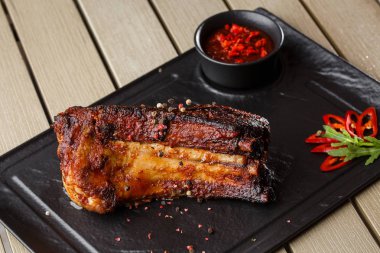 Izgara ve barbekü sıcak domuz kaburga sıcak biber ve siyah taş arka plan üzerinde sıcak sos ile. Izole. Erkekler için yemek. Baharatlı