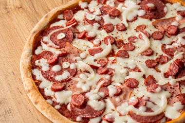 Biber, sıcak sosis, soğan, jambon, salam, sarımsak, domates ve peynir ile pizza üst görünümü.