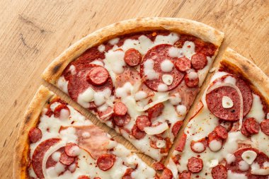 Biber, sıcak sosis, soğan, jambon, salam, sarımsak, domates ve peynir ile pizza üst görünümü. 