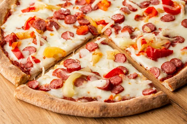 Top view of hot pizza with chili pepper , hot sausages, onion, tomatoes and cheese.