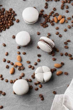Fransız makaronlar kahve çekirdekleriyle izole edilmiş. Seçici odak. gri tonda macaroon. Gri taş arka plan üzerinde Fransız çarpışma makaronlar. Şık düzenleme tatlı. Düz döşeme, üst görünüm.
