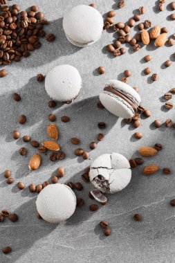 Fransız makaronlar kahve çekirdekleriyle izole edilmiş. Seçici odak. gri tonda macaroon. Gri taş arka plan üzerinde Fransız çarpışma makaronlar. Şık düzenleme tatlı. Düz döşeme, üst görünüm.