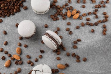 Fransız makaronlar kahve çekirdekleriyle izole edilmiş. Seçici odak. gri tonda macaroon. Gri taş arka plan üzerinde Fransız çarpışma makaronlar. Şık düzenleme tatlı. Düz döşeme, üst görünüm.