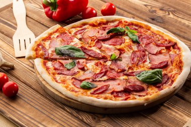 Jambon ile Pizza , sıcak sosis, salam ve mozzarella ahşap arka plan yakın. İtalyan mutfağı. Ahşap masa üzerinde prosciutto ve salam ile Pizza. üst görünüm.