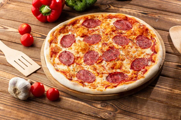 Ahşap masada lezzetli sıcak ev yapımı Pepperoni pizza. Pepperoni Pizza - Kopya alanı ile rustik siyah taş arka plan üzerinde pepperoni, peynir ve domates soslu taze ev yapımı pizza.