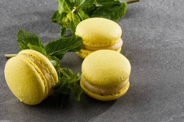 Fransız kurabiyeleri izole edilmiş. Seçici odaklanma. Gri taşlı arka planda nane şekerli güzel sarı badem kurabiyeleri. Güzel bir düzenleme. Düz yerde, üst tarafta. Makro fotoğraf.