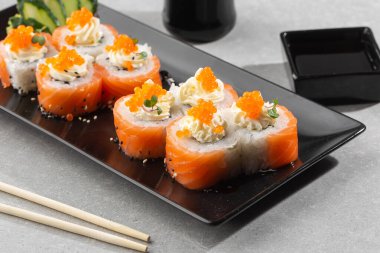 Somon, avokado, krem peynir ve kırmızı havyarlı Philadelphia usulü suşi. Suşi menüsü. Kara tabakta. Geleneksel Japon deniz ürünleri, sağlıklı gıda konsepti. Beyaz arkaplanda üst görünüm yatay fotoğraf.