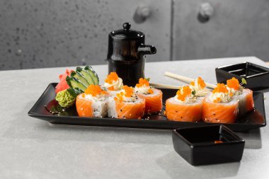 Somon, avokado, krem peynir ve kırmızı havyarlı Philadelphia usulü suşi. Suşi menüsü. Kara tabakta. Geleneksel Japon deniz ürünleri, sağlıklı gıda konsepti. Beyaz arkaplanda üst görünüm yatay fotoğraf.