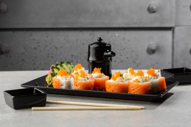 Somon, avokado, krem peynir ve kırmızı havyarlı Philadelphia usulü suşi. Suşi menüsü. Kara tabakta. Geleneksel Japon deniz ürünleri, sağlıklı gıda konsepti. Beyaz arkaplanda üst görünüm yatay fotoğraf.