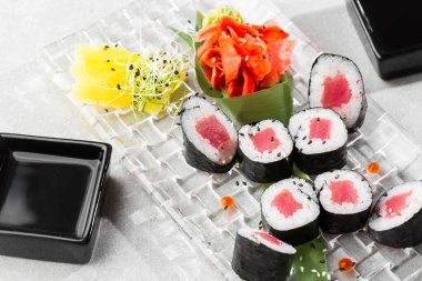 Şeffaf tabakta servis edilen ton balıklı Maki suşi ruloları. Lezzetli geleneksel Japon yemekleri, lezzetli deniz ürünleri, restoran konsepti, yemek geçmişi. yatay resim