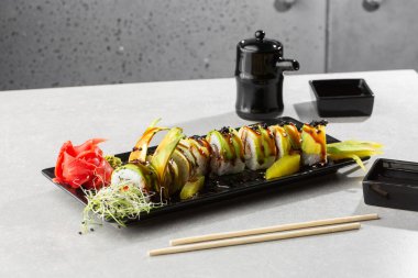 Yılan balığı, salatalık, siyah susam tohumu ve havyar ve Japon yemeği ile yeşil ejderha suşisi rulosu. Geleneksel Asya pirinç suşisi sağlıklı deniz ürünleri. Gri arka plan. Yatay fotoğraf.