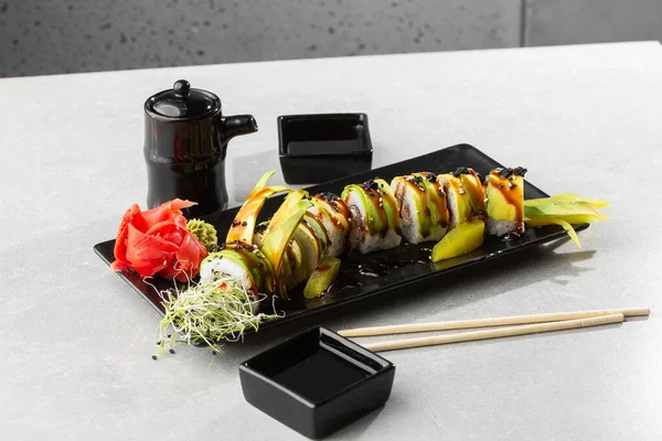 Yılan balığı, salatalık, siyah susam tohumu ve havyar ve Japon yemeği ile yeşil ejderha suşisi rulosu. Geleneksel Asya pirinç suşisi sağlıklı deniz ürünleri. Gri arka plan. Yatay fotoğraf.