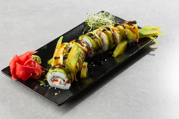 Yılan balığı, salatalık, siyah susam tohumu ve havyar ve Japon yemeği ile yeşil ejderha suşisi rulosu. Geleneksel Asya pirinç suşisi sağlıklı deniz ürünleri. Gri arka plan. Yatay fotoğraf.