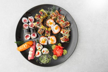Japon suşi seti. Taze ton balığı maki, somon nigiri ve siyah tabakta servis edilen ejderha suşi ruloları. Üst görünümün yatay üst görüntüsü düz yatıyordu. Büyük bir şirket için bir set..