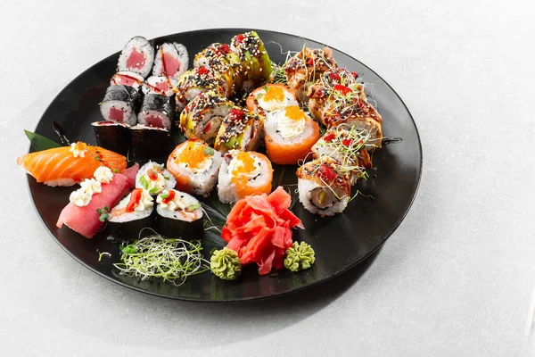 Japanese sushi set. Set of fresh tuna maki , salmon nigiri and dragon sushi rolls served on black plate close-up. Horizontal top view from above Top view flat lay. A set for a large company.