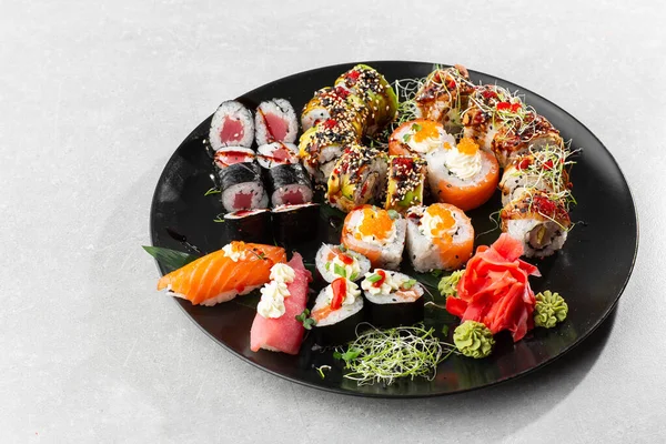 Japanese sushi set. Set of fresh tuna maki , salmon nigiri and dragon sushi rolls served on black plate close-up. Horizontal top view from above Top view flat lay. A set for a large company.