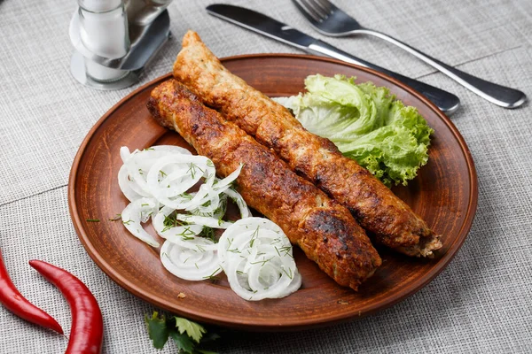 Shish kebab from ground beef meat. Lula kebab with white onion and salade, traditional Caucasian dish. Lined on a beautiful clay plate. horizontal photo. grey background. top view. — Stok Foto
