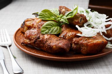 Kahverengi kil kasede ızgara domuz pirzolası. Izgara domuz pirzolası ve soğan ve fesleğenli tabağın önü. Gri arka plan. yatay fotoğraf. Üst görünüm