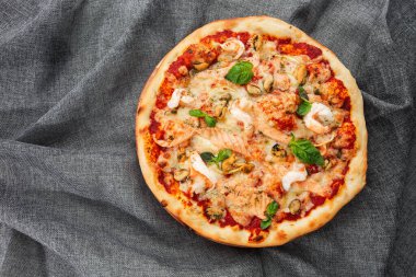 Karides, kalamar, midye, taze otlar ve mozzarellalı İtalyan usulü deniz ürünleri pizzası. Gri arka planda yukarıdan izleniyor. Yatay fotoğraf.