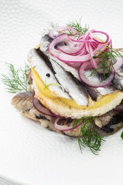 Aperatif yemek, tuzlanmış ringa balığı, tereyağı ve beyaz tabakta kırmızı soğan. Seçici odaklanma. Yukarıdan dikey görüş, üst çekim. Beyaz arkaplan.
