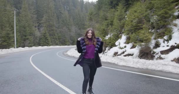 Dziewczyna uśmiecha się do kamery i zakłada kaptur na tle zimowego lasu. Glamorous śmieszne młoda kobieta z uśmiechem na sobie stylowy sweter, fioletowy modne futro. Futro i koncepcja mody. 4k — Wideo stockowe