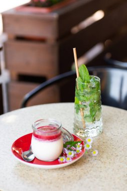 Vanilyalı Panna Cotta ve cam kavanozda jöle. İtalyan tatlı panna cotta. Klasik İtalyan tatlı kremalı panna cotta vişne soslu. Pasta salonu kavramı. Mojito ve tatlı..