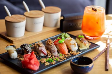 Şeffaf tabakta servis edilen somon, yılan balığı, ton balığı ve karidesli Nigiri suşisi. Lezzetli geleneksel Japon yemekleri, lezzetli deniz ürünleri, restoran konsepti, yemek geçmişi..