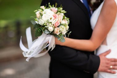 Güzel bir düğün çifti el ele tutuşuyor ve çiçekler açıyor. Çok heyecanlı bir an. Klasik gelinlik ve erkek kostümü. Düğün salonu reklamı için. Düğün afişi. Yatay